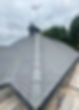 A grey, neatly tiled roof with uniform shingles under a cloudy sky
