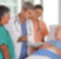 A doctor and two nurses stand beside an elderly patient