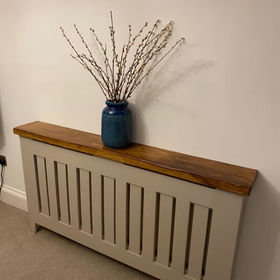 A blue vase on a radiator covered with a wooden structure 
