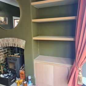 An empty built-in wooden shelves next to a fireplace
