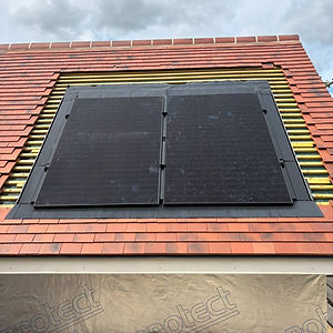 Two black solar panels are integrated into a red-tiled roof
