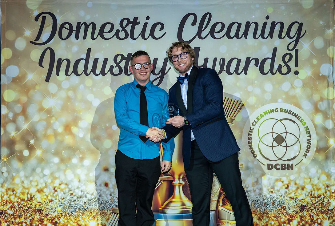 Two men in formal attire shake hands at the Domestic Cleaning Industry Awards