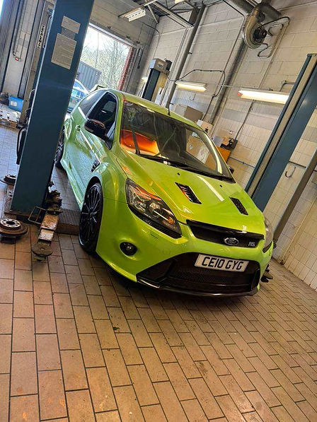 A bright green Ford Focus RS is parked in a garage