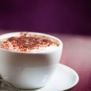 A close-up of a white cup of cappuccino with a dusting of cocoa powder