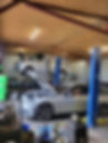 Car repair workshop with a van on a lift and a car with an open hood