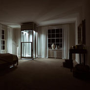 Dimly lit room with a modern glass elevator in the center