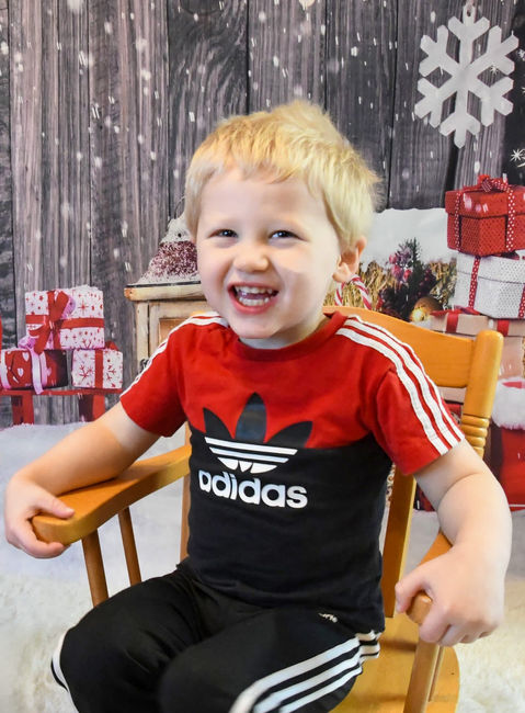 A little boy smiling and sitting in a chair