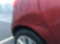 The side view of a red car with dents