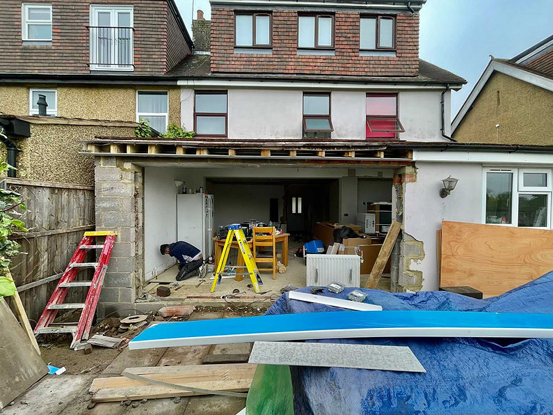 A partially renovated two-story house with an exposed garage under construction
