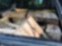 A pile of various wooden logs and planks in a trailer