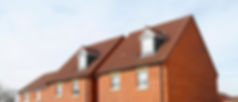 Red-brick townhouses with brown tiled roofs, featuring small dormer windows