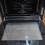 Open black oven with a metallic handle and dials, viewed from the front