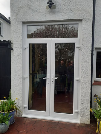 Double glass doors on a white building facade with reflections