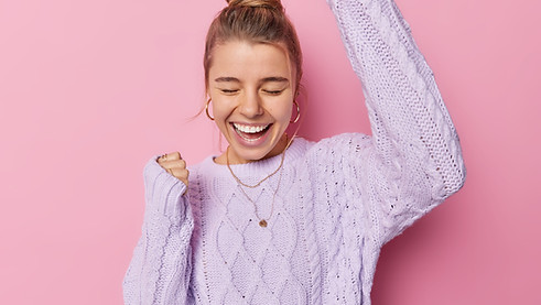 indoor-shot-of-optimistic-young-woman-with-bun-hairstye-makes-yes-gesture-laughs-positivel