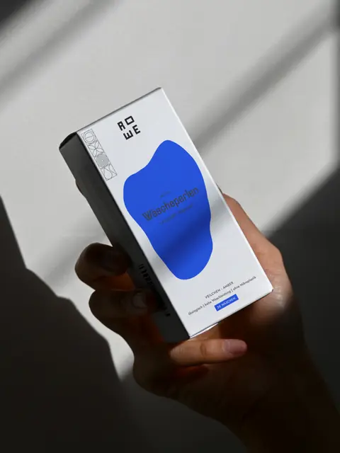 Hand holding minimalist packaging with cobalt blue design elements, part of the ROWE brand and packaging system