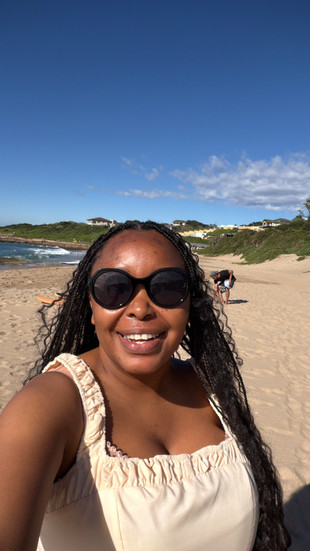A woman wearing sunglasses, smiling and joyful by the beach