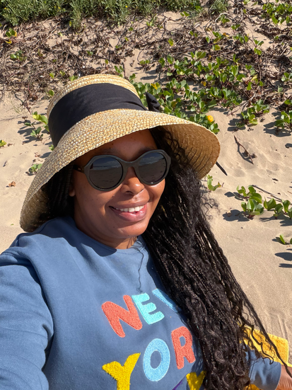 A woman wearing a hat with sunglasses and smiling
