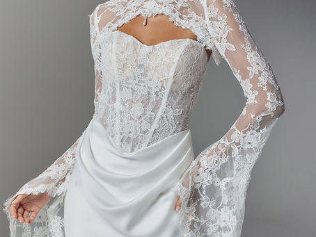 model wears on trend wedding dress with draped satin skirt, corseted basque waist lace bodice and detachable high neck lace top with full length lace sleeves