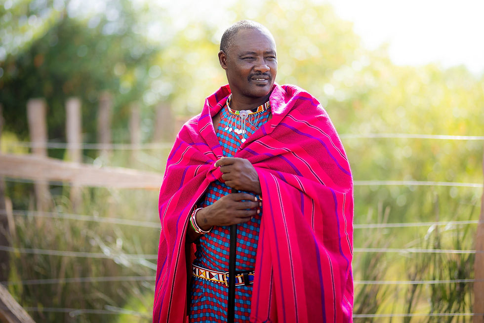 Ole Keiwa Maasai Elder and Director of Culture and Language wearing shuka smiling with sun behind