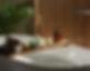 Wooden bath tray with candle, air freshener and bathroom amenities on tub indoors_edited.j
