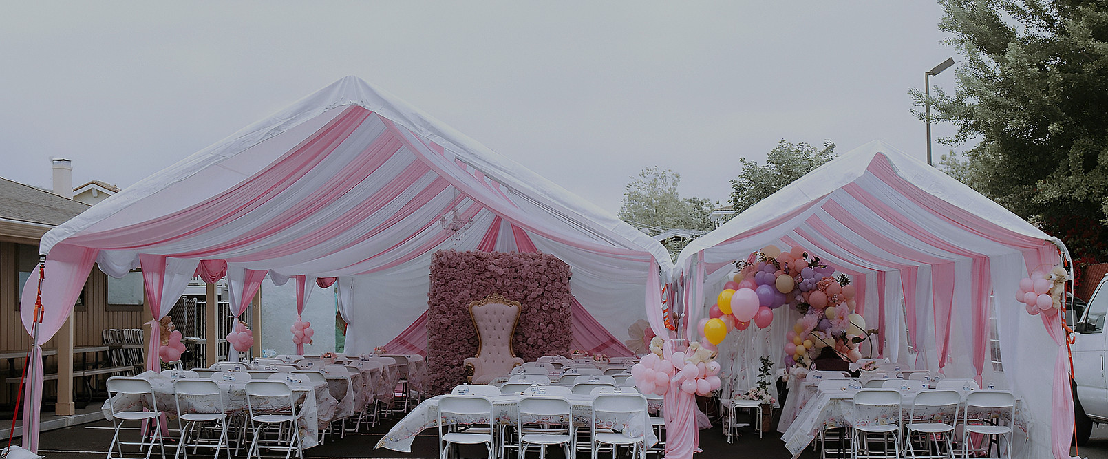 Custom pink and white draped canopy rental featuring tables, chairs, balloon decorations, and a floral backdrop for birthdays