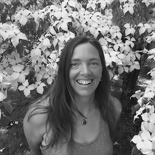 Pilates and yoga instructor Cobi smiling in front of some flowers
