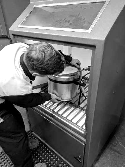Technician positioning a diesel particulate filter inside a cleaning cabinet