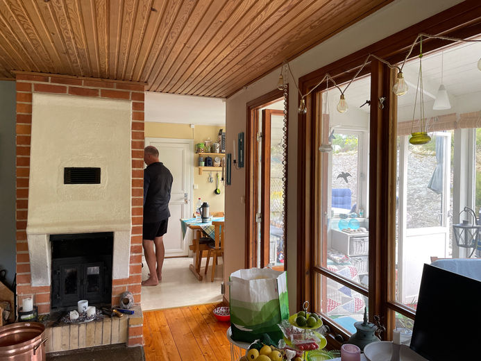 Vardagsrum med öppen spis i fritidshus i Uttervik före renovering.