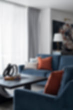 Classic lounge room design by Porch Light Interiors in Brisbane , featuring custom sofa in blue velvet, rust coloured cushion , sculpture on timber coffee table