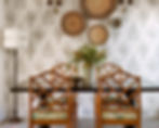 Classic dining room design by Porch Light Interiors in Brisbane featuring cane vintage dining chairs with textile seat cushion, botanic leaf wallpaper, raffia woven wall baskets, wall sconces. rustic vase and black stained pedestal dining table