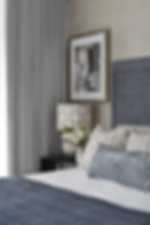 Classic bedroom design by Porch Light Interiors in Brisbane featuring Grey custom bedhead, custom cushions and lamp shade, abstract art, block out curtains
