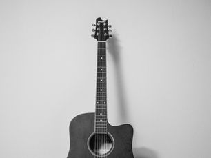 Black-and-white acoustic guitar leaning against a plain wall, with ARGENT on the headstock and TOMMI-17 visible in the sound hole.