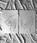 two black and white drawings of a woman 's face are sitting on a bed .