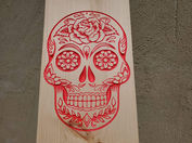 a wooden board with a sugar skull carved into it