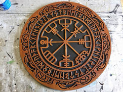 a wooden plaque with a compass and runes on it