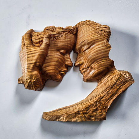 a wooden sculpture of a man and woman looking at each other