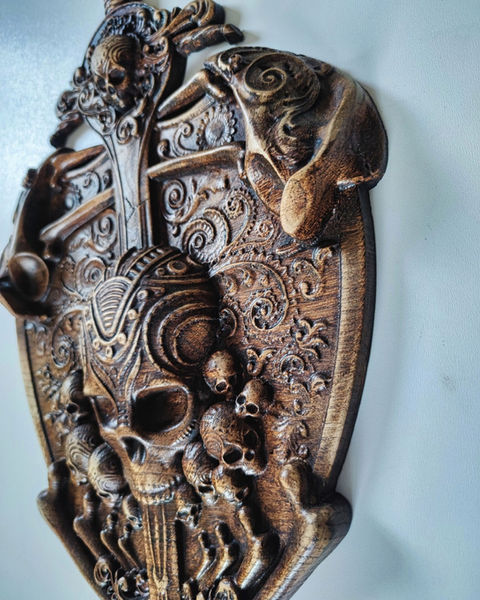 a wood carving with skulls and swirls on it