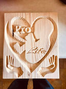 a wooden plaque with a heart and hands carved into it .