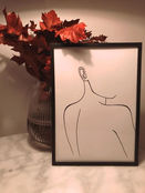 a drawing of a woman 's back is sitting on a table next to a vase of flowers .