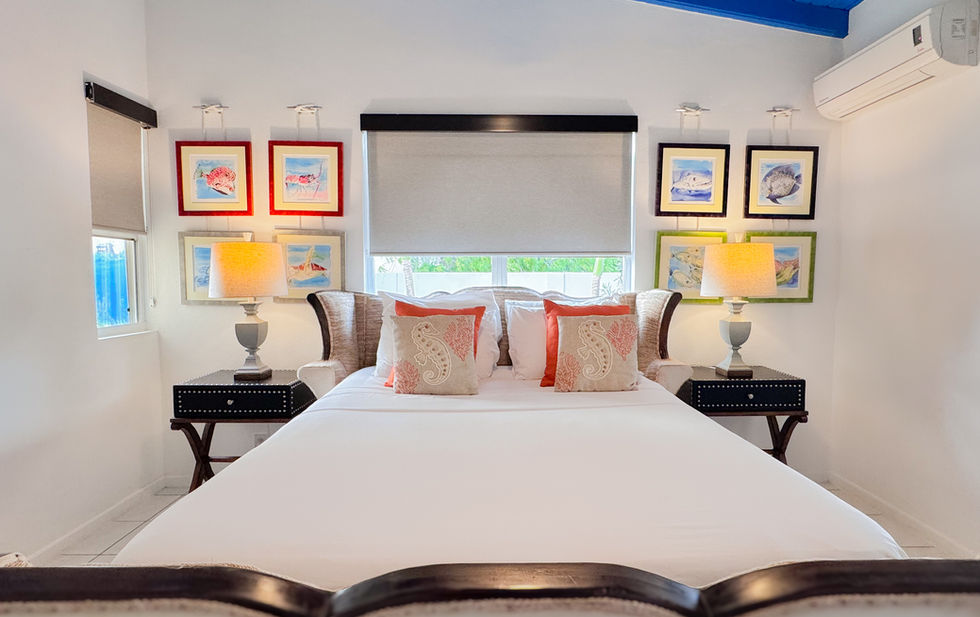 Kas di Amor's inviting bedroom features coastal decor, sea life watercolor paintings, air conditioning, and a cooling ceiling fan.