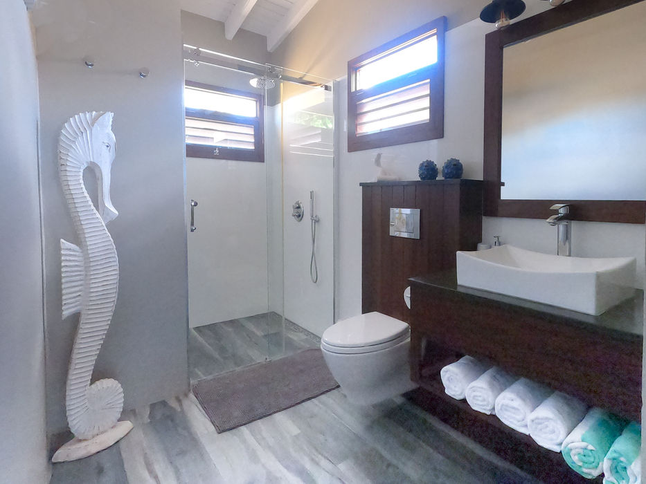 The ensuite bathroom features a refreshing rain shower, an elegant wood vanity, a stylish mirror, and a ceiling fan for your comfort.