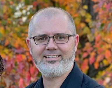 Smiling man with glasses and beard, autumn background