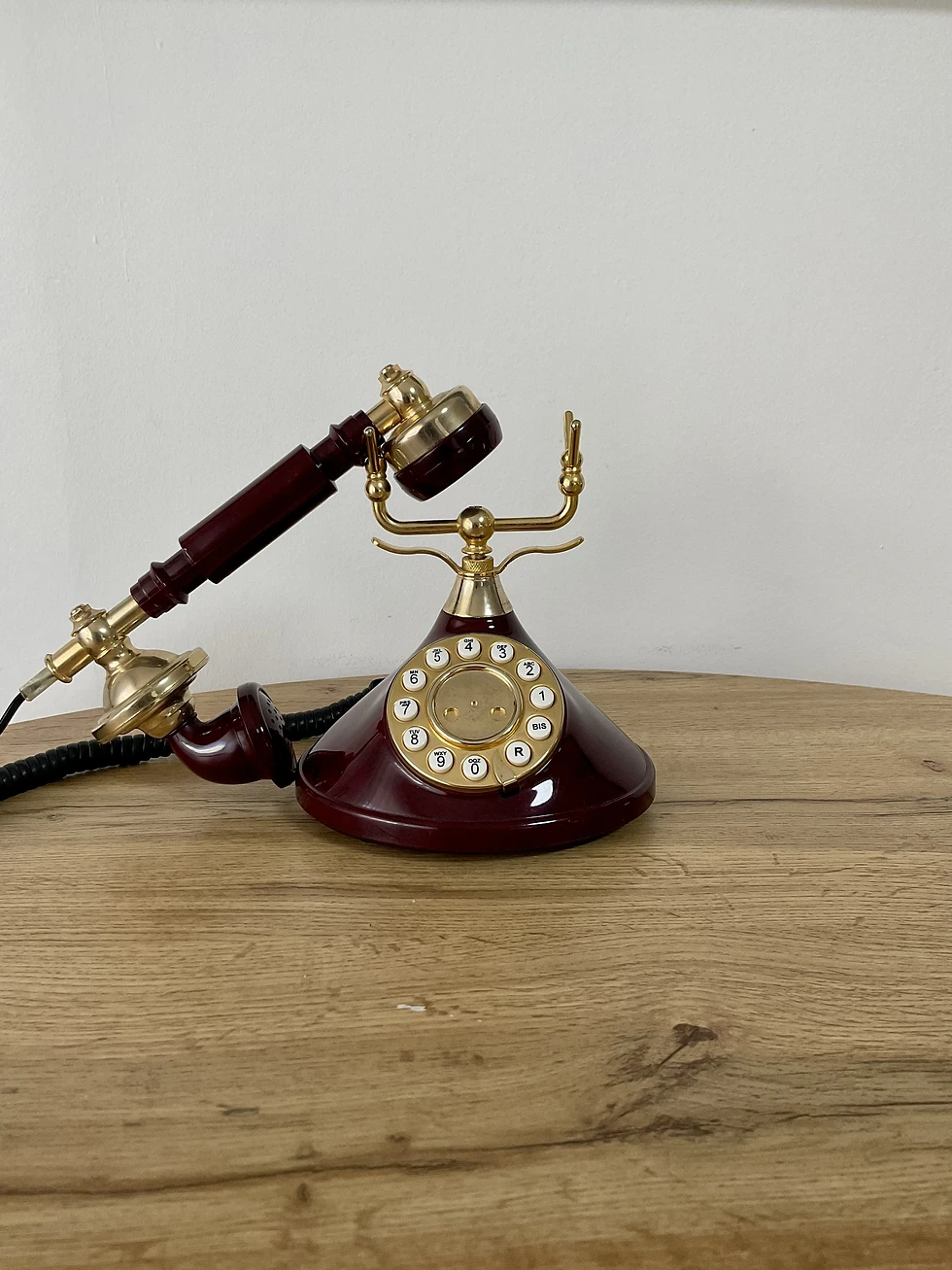 Téléphone de 1997 vintage or et bordeaux avec le combiné à demi posé sur son socle