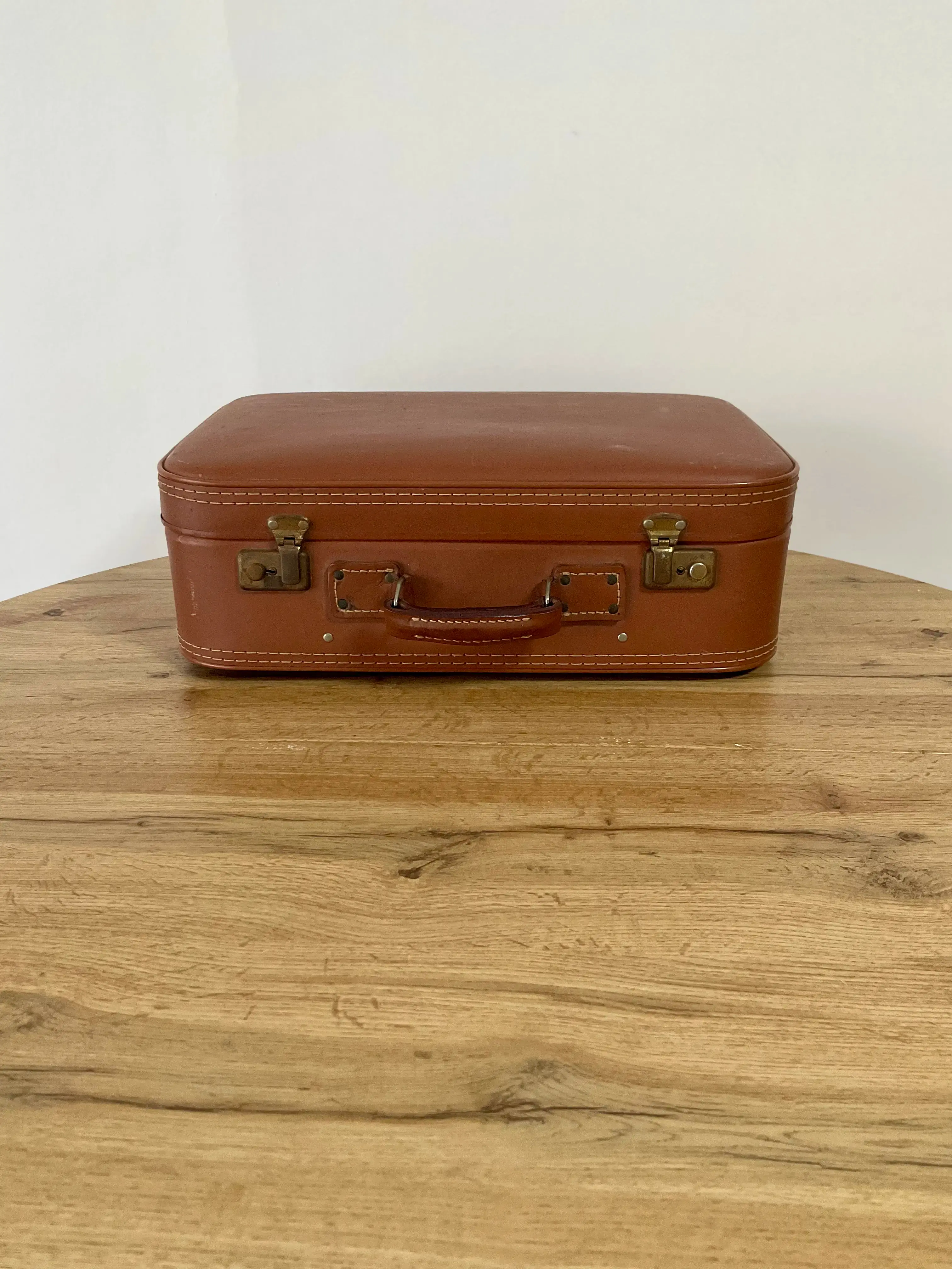 valise en cuir marron claire fermé sur une table en bois