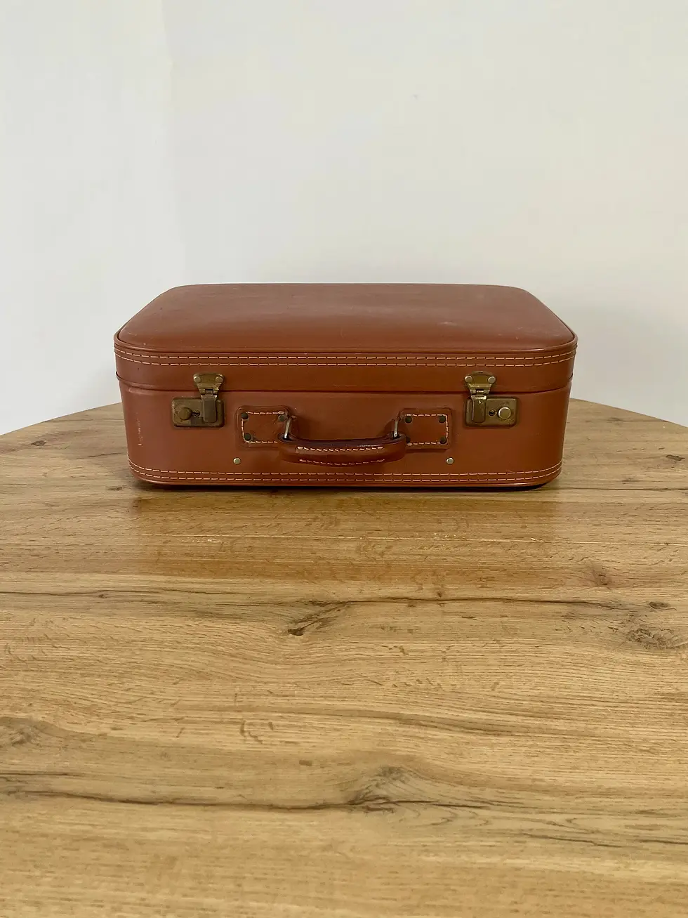 valise en cuir marron claire fermé sur une table en bois