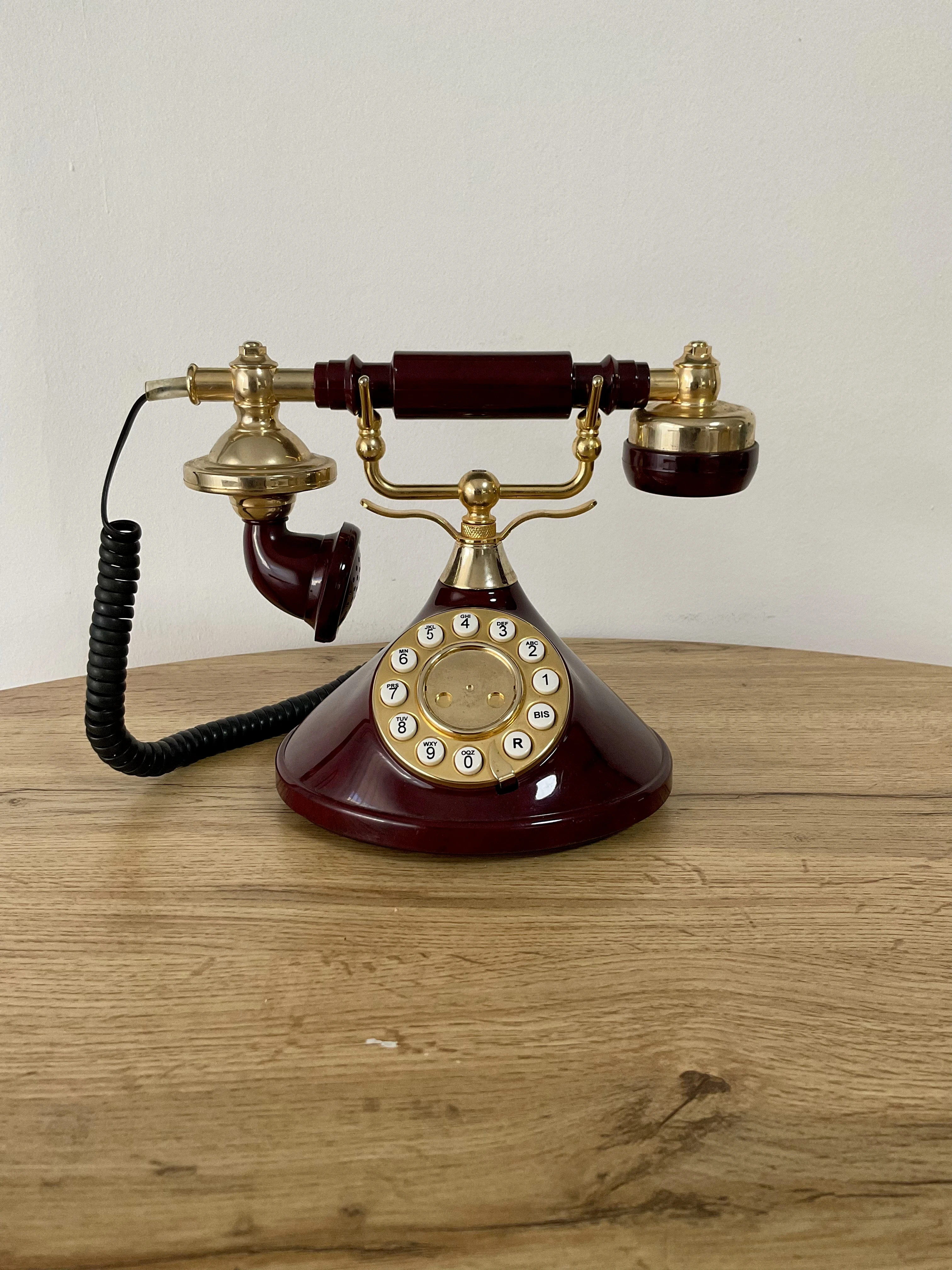 Téléphone de 1997 vintage bordeaux et or avec le combiné posé sur son socle
