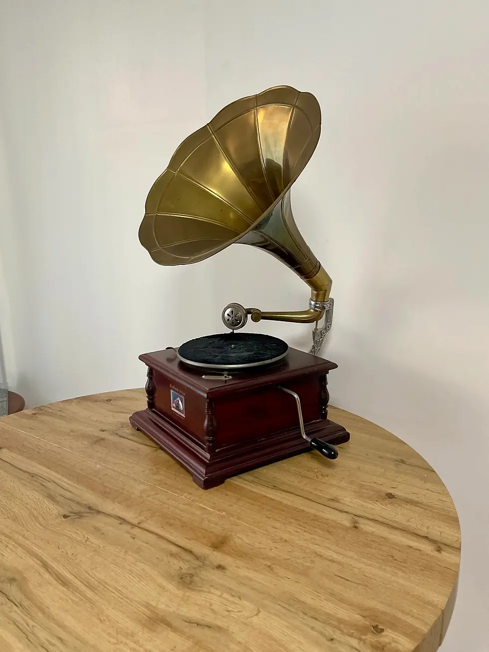 Gramophone bordeaux et or vue de 3/4 posé sur une table