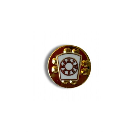 A gilt and white enamelled lapel pin in the shape of a keystone.