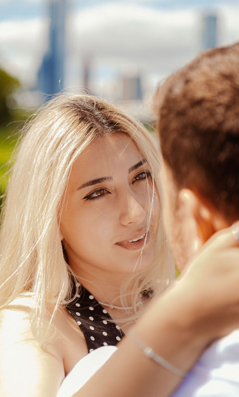 Woman looking at man with city background.