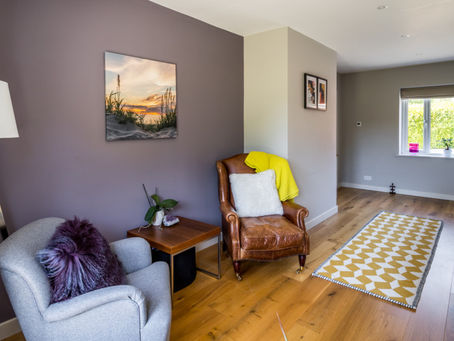 Calm corner in a modern home with armchair, soft lighting and natural light, designed for reading and relaxation.